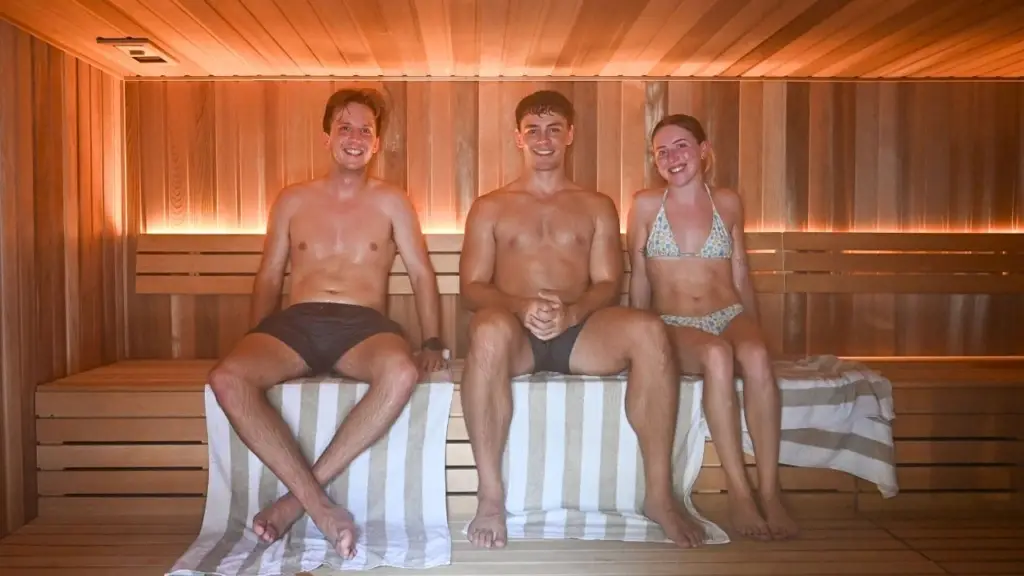 A group of friends engaged in conversation inside Vikasati's sauna, about "How long should you stay in a sauna?"