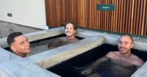 Three men unwind in an ice bath, using it as a reset tool after a challenging mental day.