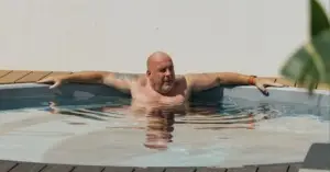 A shirtless man is in a swimming pool, illustrating the benefits of hot vs. cold magnesium pools for wellness on the Gold Coast.