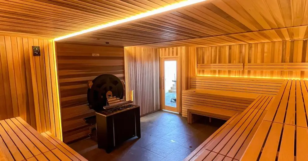 A serene finnish sauna room, featuring wooden benches and soft lighting, perfect for relaxation and wellness.