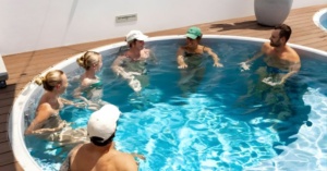 Six people discuss bathhouse etiquette in Australia while standing in a sunny circular pool.