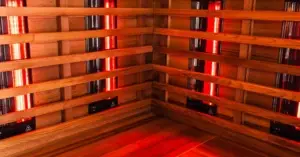Wooden infrared sauna interior with red glowing heater panels, perfect before an ice bath session.