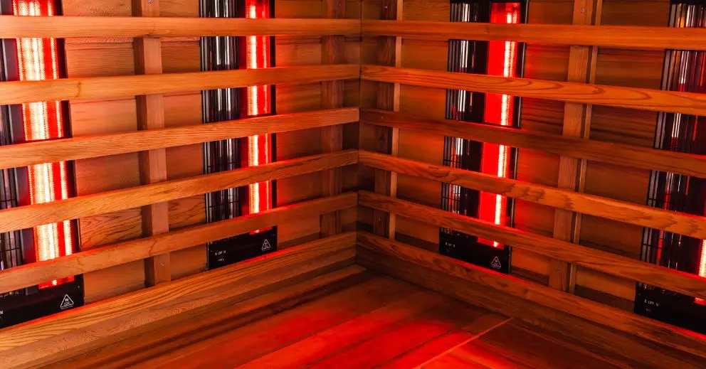 Wooden infrared sauna interior with red glowing heater panels, perfect before an ice bath session.