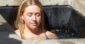 Person with closed eyes sits in a small tub, trying ice baths for runners recovery.