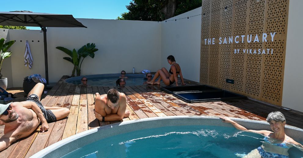People enjoying a weekend wellness plan in hot tubs on the wooden deck at The Sanctuary by Vikasati.