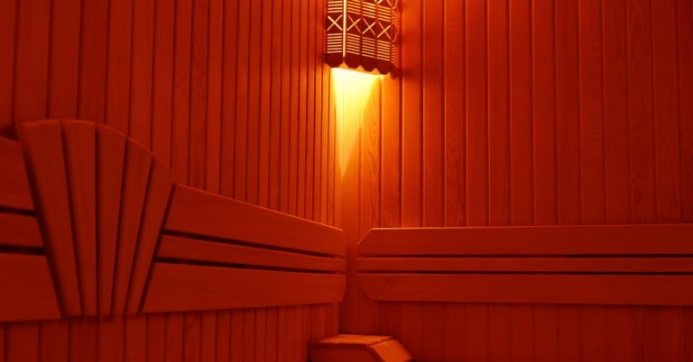 Wood-paneled infrared sauna with benches boosts circulation under a warm, wall-mounted light.