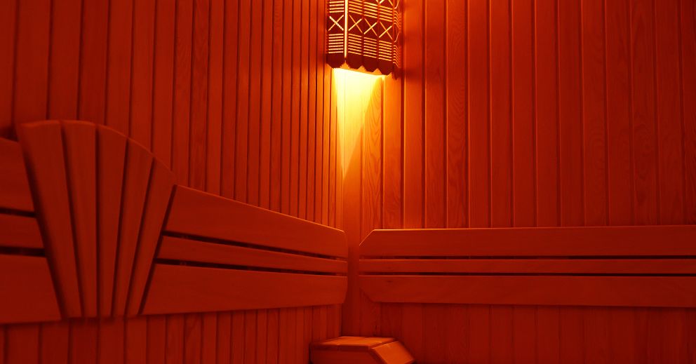 Wood-paneled infrared sauna with benches boosts circulation under a warm, wall-mounted light.