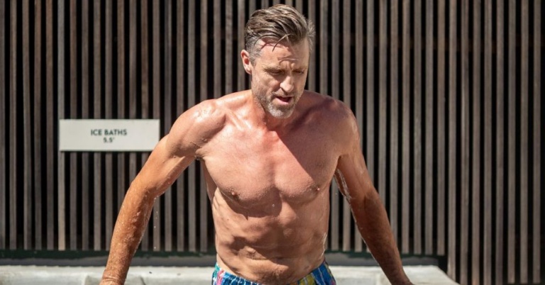 Shirtless man emerging from an ice bath, perfect for contrast therapy for beginners.