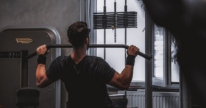 Person using a lat pulldown machine in a gym, benefits from ice baths for strength training.