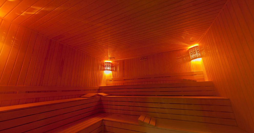 Wood-paneled infrared sauna for stiffness with tiered benches and warm, dim lighting.