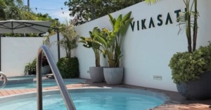 Small round pool with metal handrail, potted plants, and a "VIKASA" sign: structured downtime.