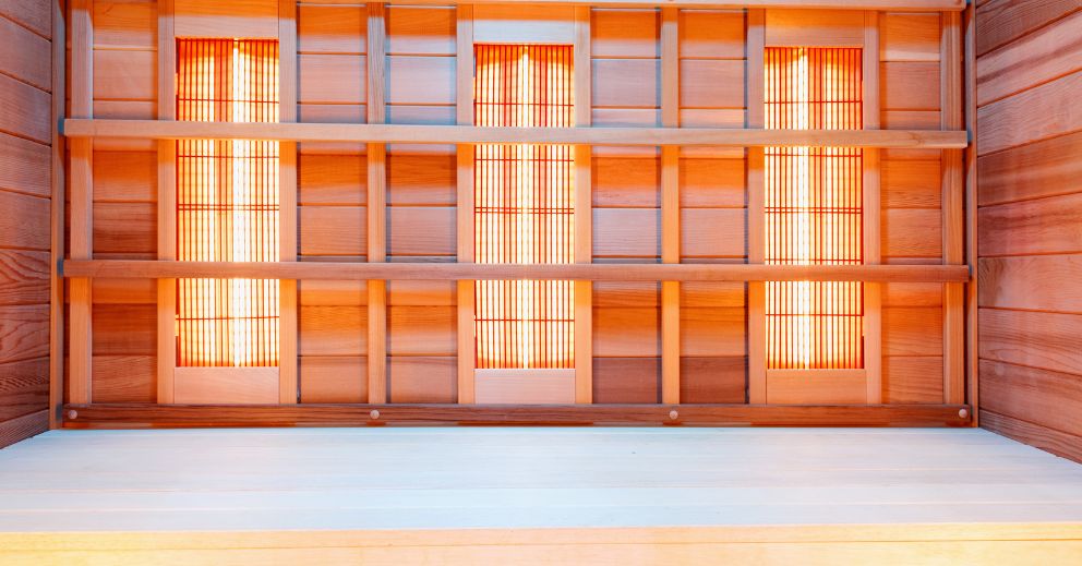 Wooden ceiling with three vertical light panels, similar to an infrared sauna, viewed from below.
