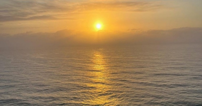 Golden sunset reflecting off the ocean near a Brisbane bathhouse.